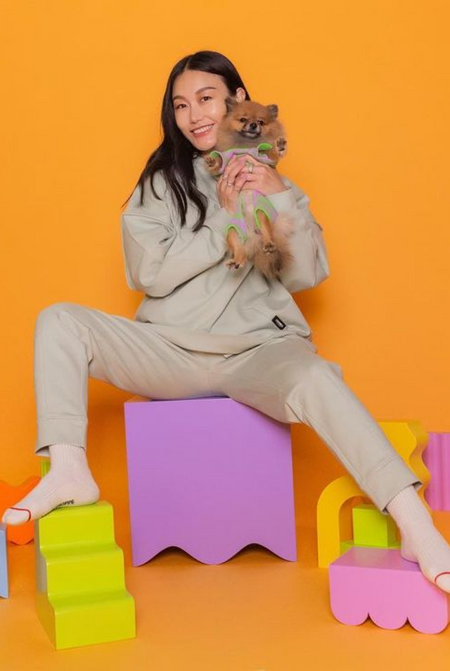 A woman holding a Pomeranian dog seating on a wavy cube and has curvy step, bumpy bundle, arc and squiggle pieces as a background set. 